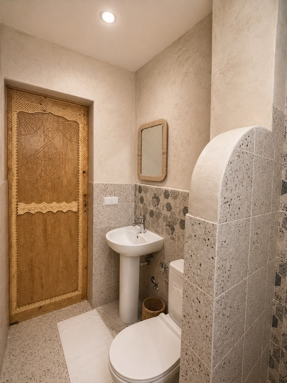 Bathroom with terrazzo tiles and a carved wooden door