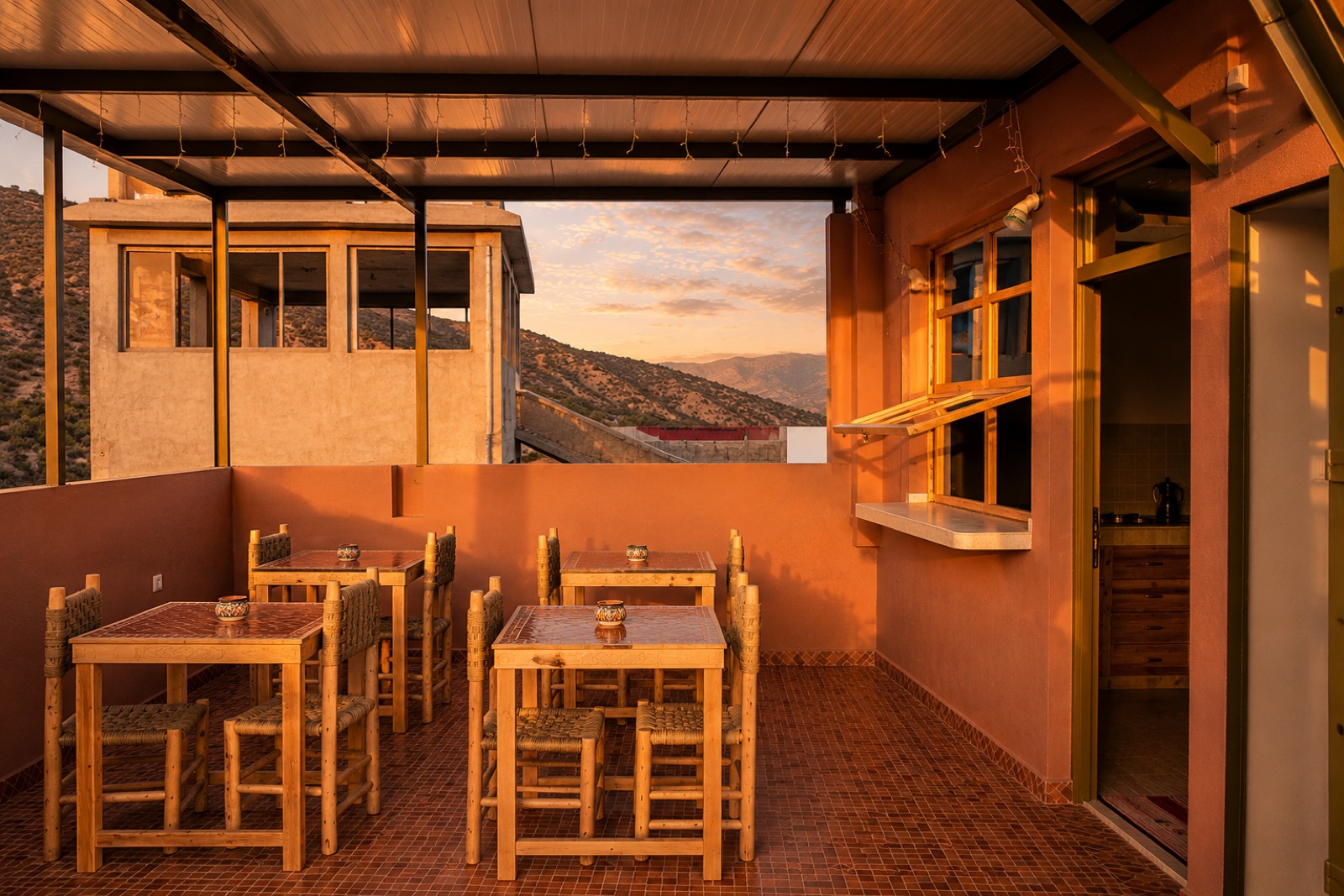 Covered terrace with wooden dining tables at sunset