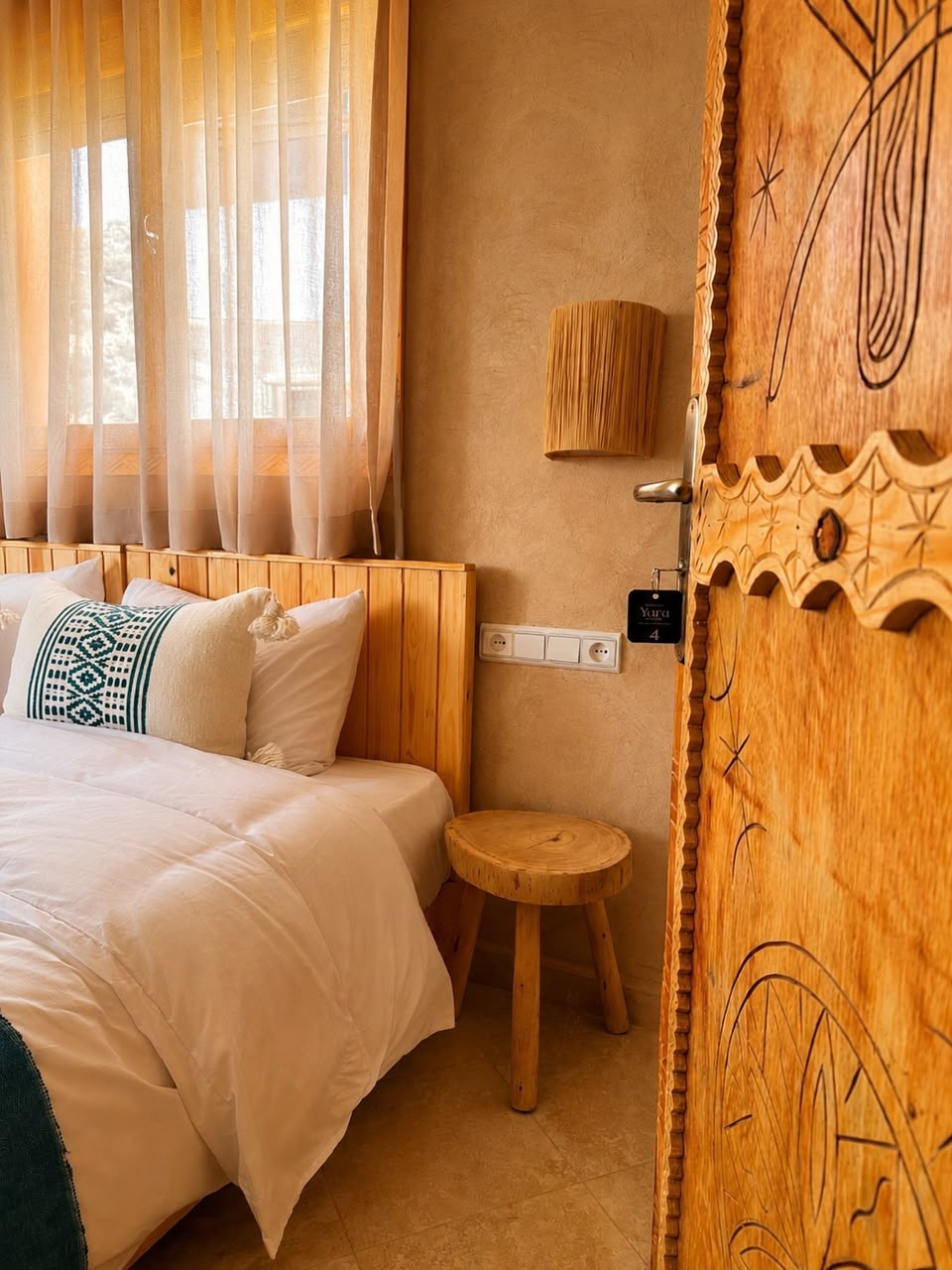 Bed in white linen beside a hand-carved wooden door