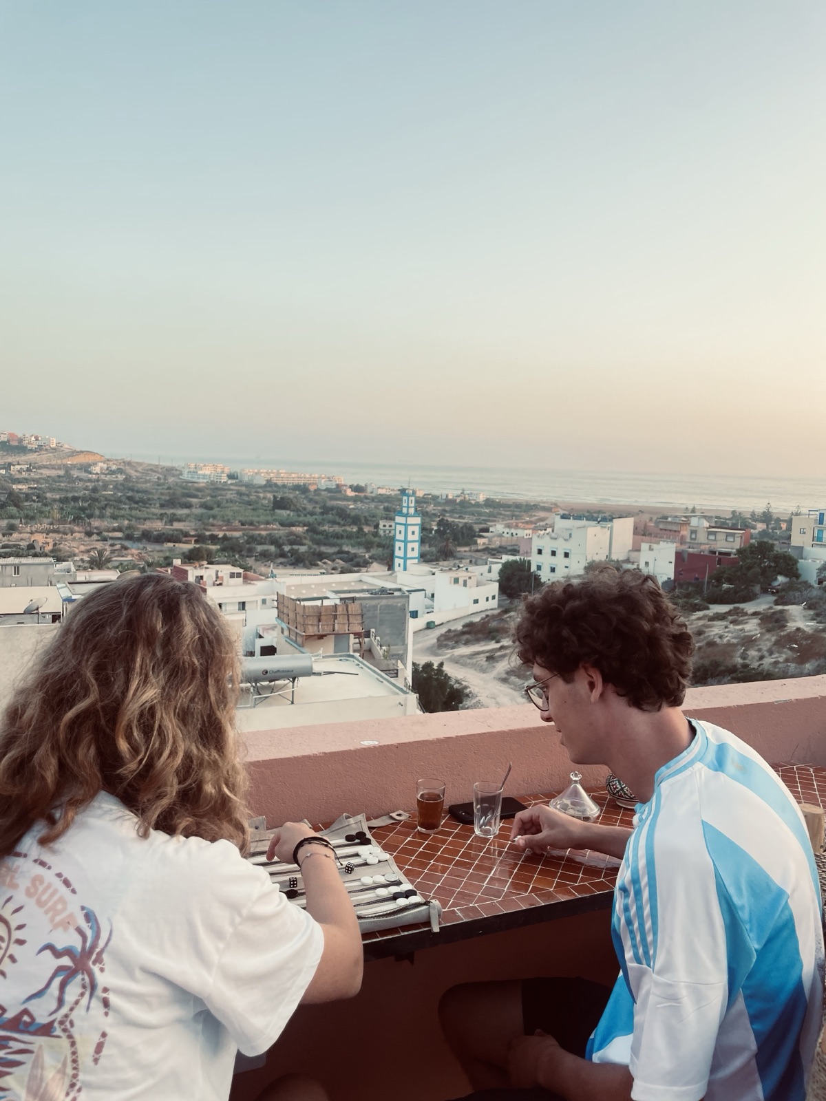 Guests relaxing on the Yara Lodge rooftop at sunset, ocean on the horizon