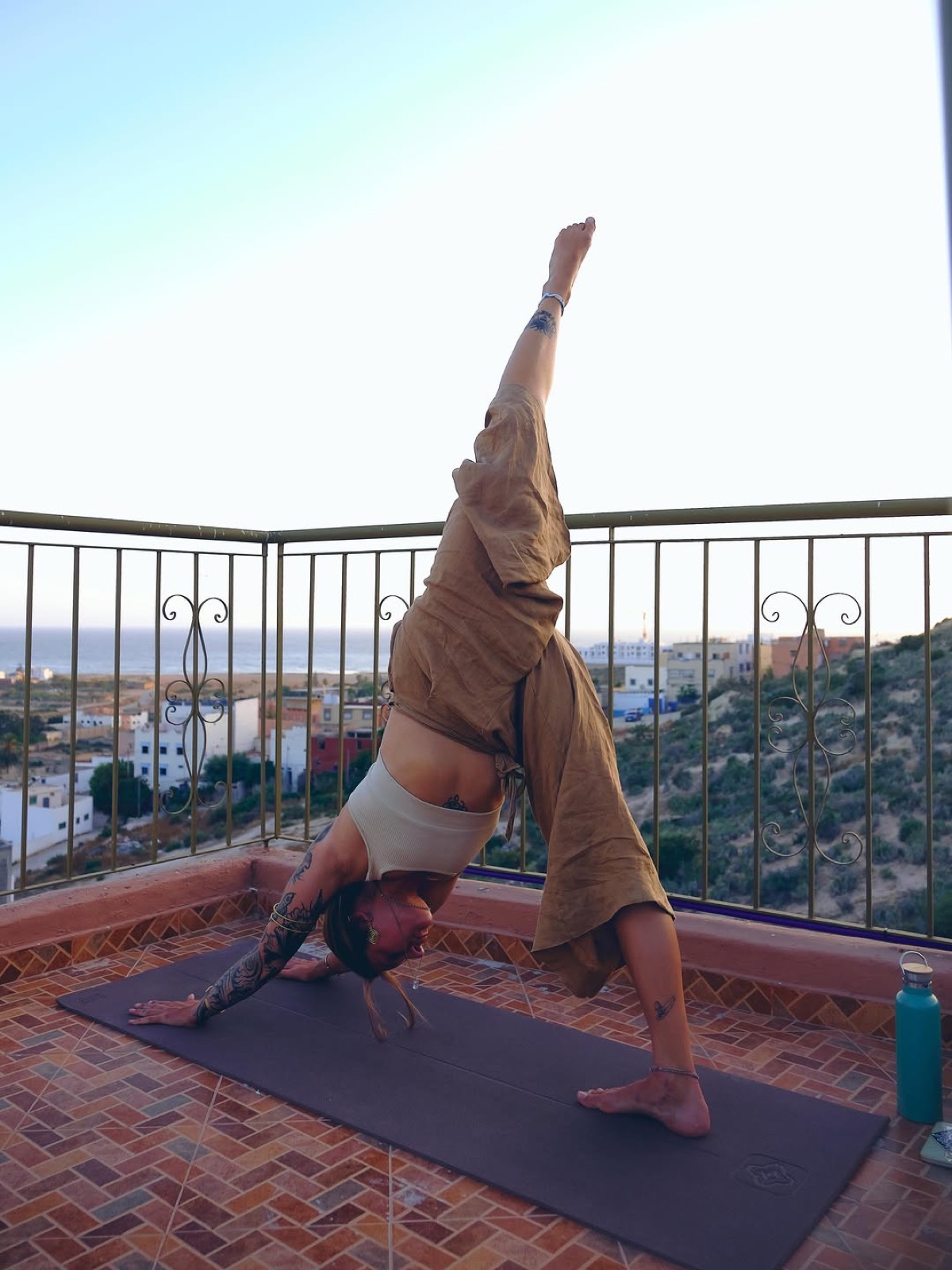 Yoga pose on the Yara Lodge rooftop with views over Tamraght to the ocean