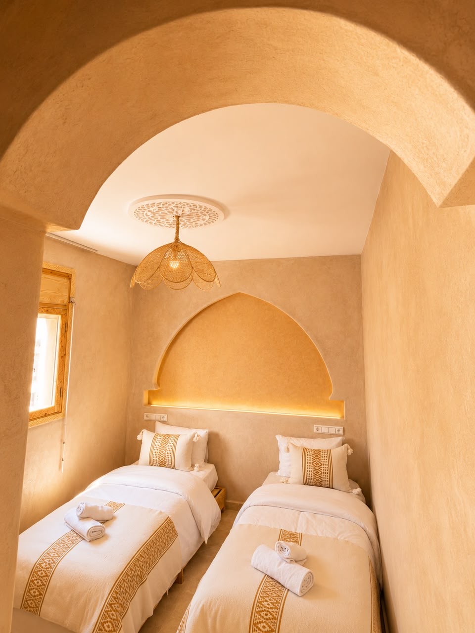 Twin room seen through an arch, with a lit arch above the beds